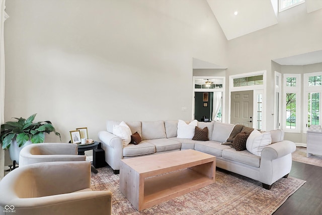 living room with high vaulted ceiling, baseboards, and wood finished floors