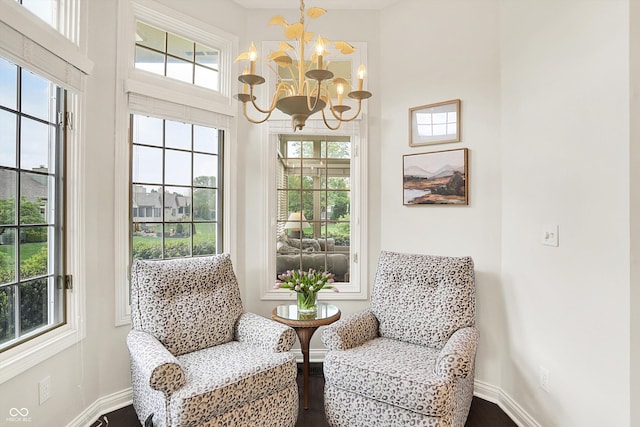 sitting room with a notable chandelier, plenty of natural light, and dark wood finished floors