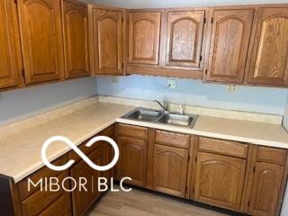 1710 S Birch St, Muncie, IN 47302 - kitchen with a sink, brown cabinetry, light countertops, and light wood-style floors