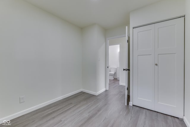 unfurnished bedroom featuring baseboards, wood finished floors, and a closet