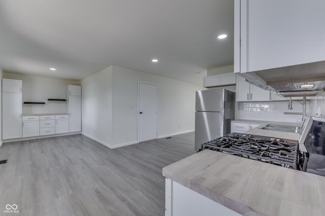 kitchen with freestanding refrigerator, baseboards, recessed lighting, white cabinetry, and light wood finished floors