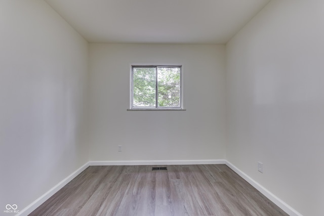 spare room with baseboards, wood finished floors, and visible vents