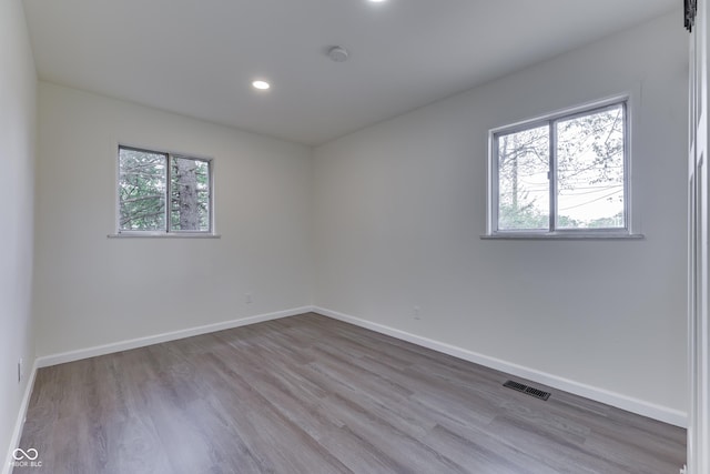 unfurnished room with baseboards, wood finished floors, and visible vents