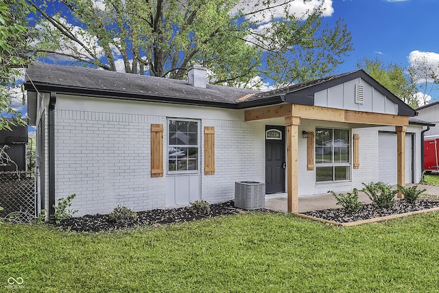 view of front of home with brick siding, a garage, a front lawn, and cooling unit