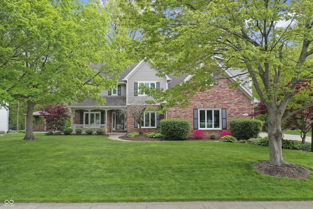 view of front of house featuring brick siding, a front lawn, and covered porch
