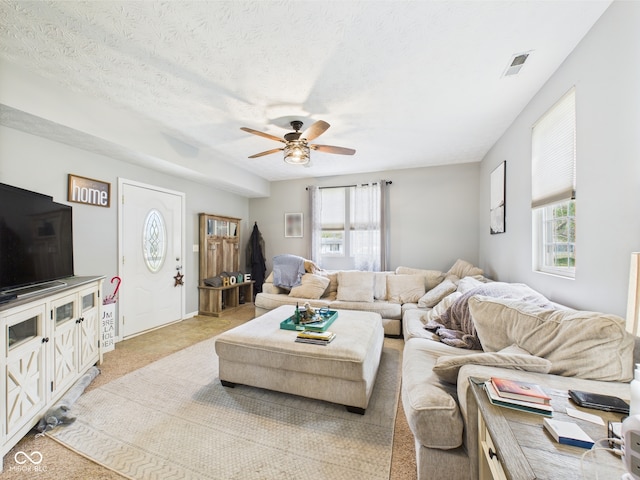 living area featuring a healthy amount of sunlight, ceiling fan, light carpet, and visible vents