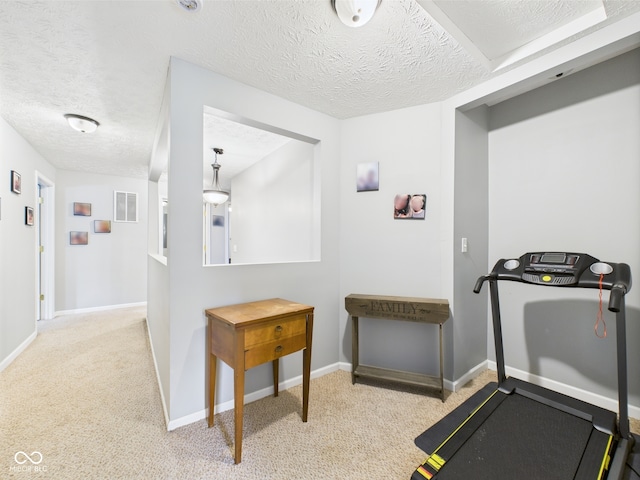workout area with baseboards, light carpet, a textured ceiling, and visible vents