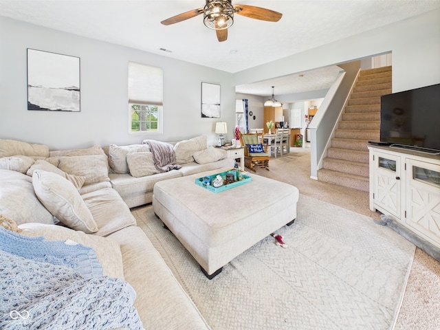 living area with ceiling fan, visible vents, light carpet, and stairway