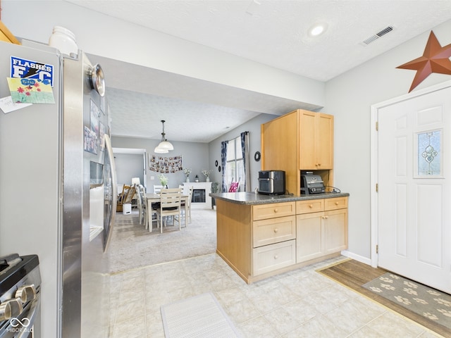 kitchen featuring dark countertops, hanging light fixtures, light brown cabinets, stainless steel appliances, and visible vents