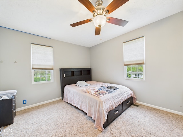 carpeted bedroom with baseboards, multiple windows, and a ceiling fan