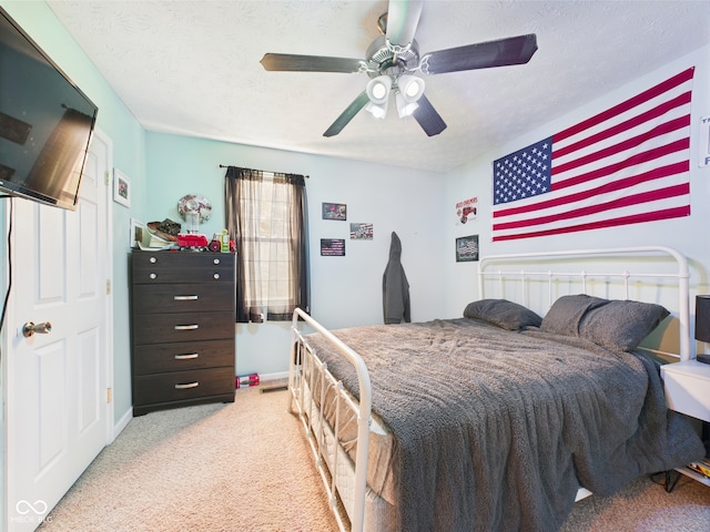 bedroom featuring baseboards, a textured ceiling, light carpet, and ceiling fan