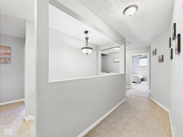 corridor with a textured ceiling, baseboards, and carpet