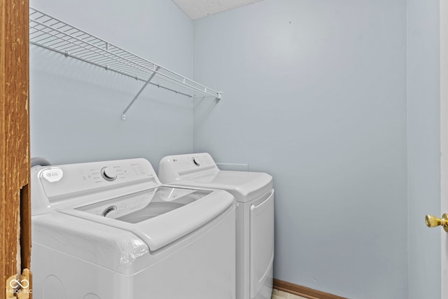 clothes washing area with separate washer and dryer, laundry area, and baseboards