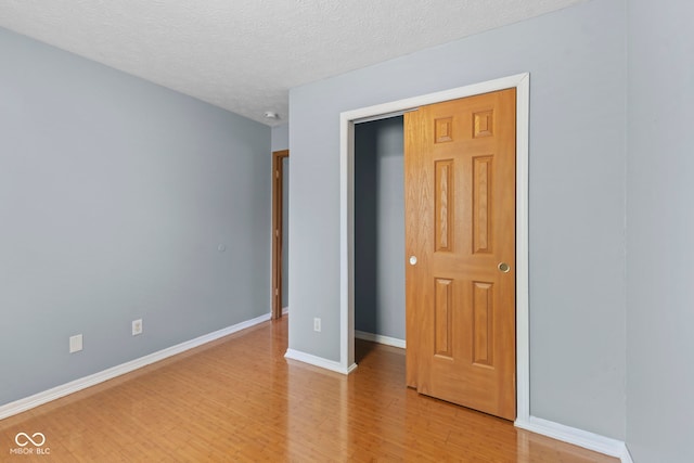 unfurnished bedroom featuring baseboards, light wood-style floors, and a textured ceiling