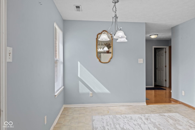 unfurnished dining area featuring baseboards and visible vents