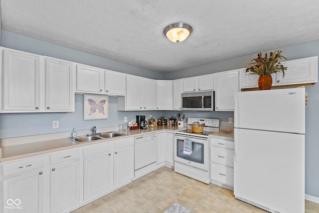 kitchen with light countertops, white cabinetry, a sink, and white appliances