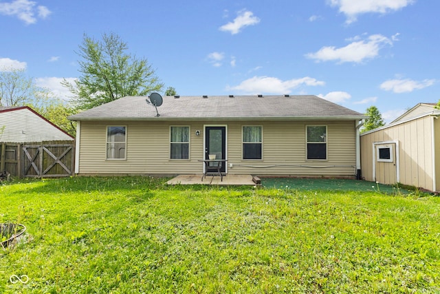 rear view of property featuring a patio, fence, a lawn, and an outbuilding