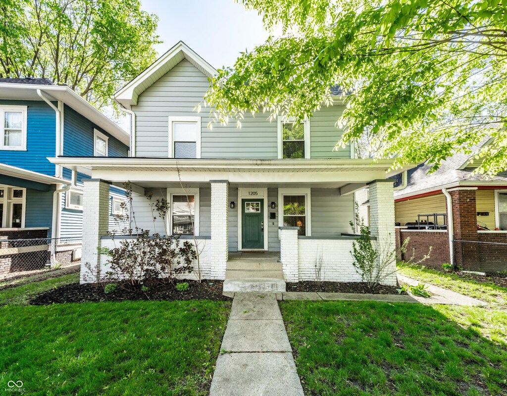 1205 N Oxford St, Indianapolis, IN 46201 - american foursquare style home featuring a porch, brick siding, fence, and a front yard