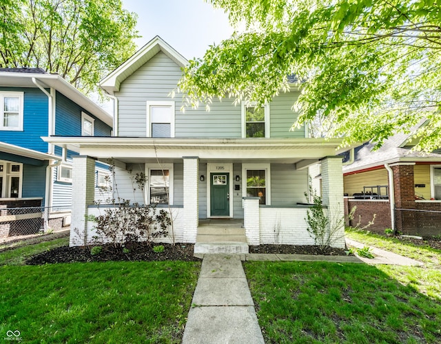 1205 N Oxford St, Indianapolis, IN 46201 - american foursquare style home featuring a porch, brick siding, fence, and a front yard