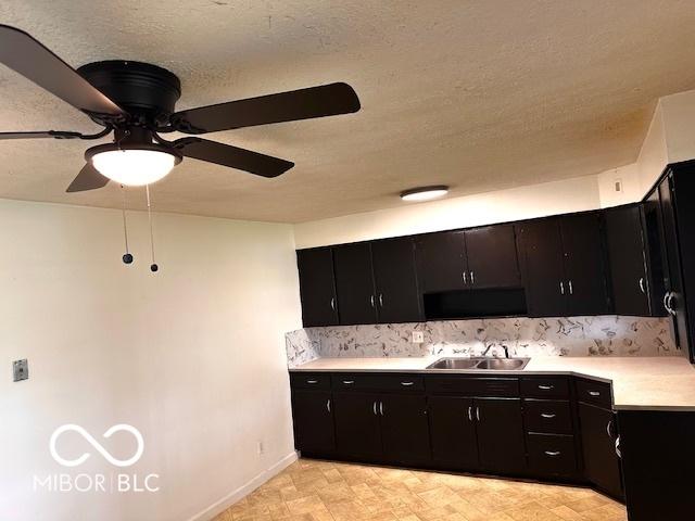 1045 13th St, Tell City, IN 47586 - kitchen with a sink, light countertops, a ceiling fan, dark cabinetry, and a textured ceiling