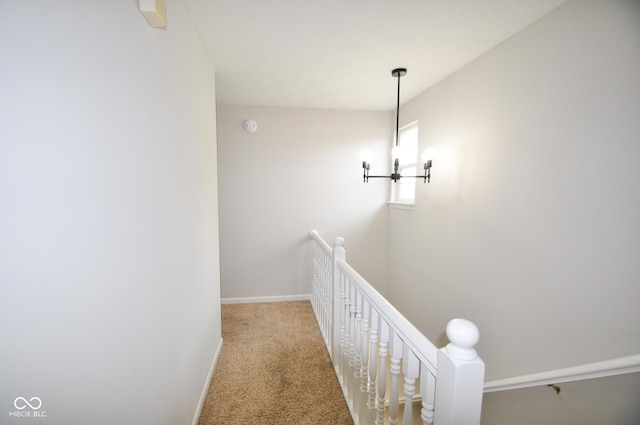 hallway featuring baseboards, carpet, and an upstairs landing