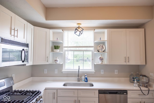 kitchen featuring white cabinets, open shelves, appliances with stainless steel finishes, a sink, and light countertops
