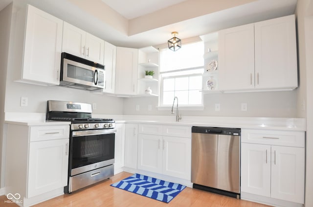 kitchen featuring white cabinets, stainless steel appliances, open shelves, and light countertops