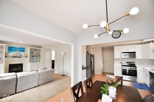 dining area featuring light wood finished floors, a tile fireplace, and a notable chandelier