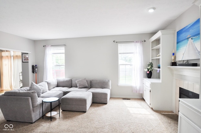 living area with baseboards, visible vents, light carpet, and a fireplace
