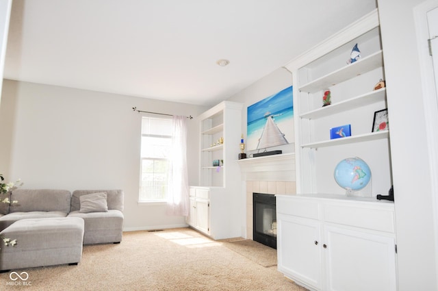 living room featuring a tiled fireplace, baseboards, and light carpet