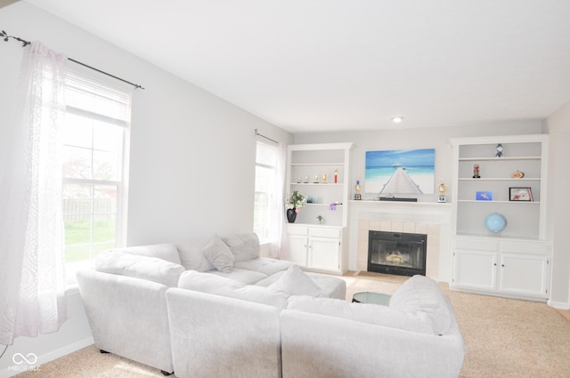 living area with light colored carpet, built in shelves, a healthy amount of sunlight, and a fireplace