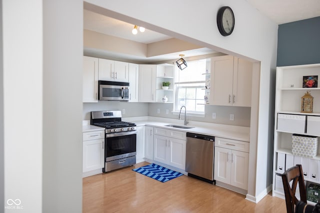 9718 Jupiter Pass, Carmel, IN 46032 - kitchen featuring stainless steel appliances, a sink, open shelves, light wood-style flooring, and light countertops