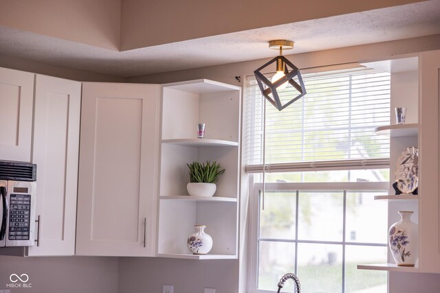 9718 Jupiter Pass, Carmel, IN 46032 - kitchen view of stainless steel microwave, open shelves, and white cabinetry