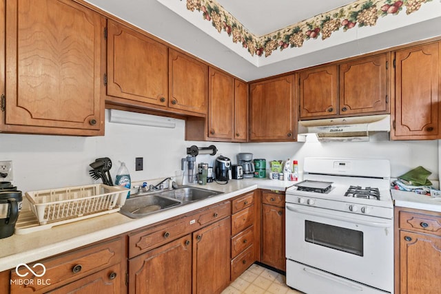 3200 Raible Ave, Anderson, IN 46011 - kitchen with under cabinet range hood, white gas range, a sink, and brown cabinets