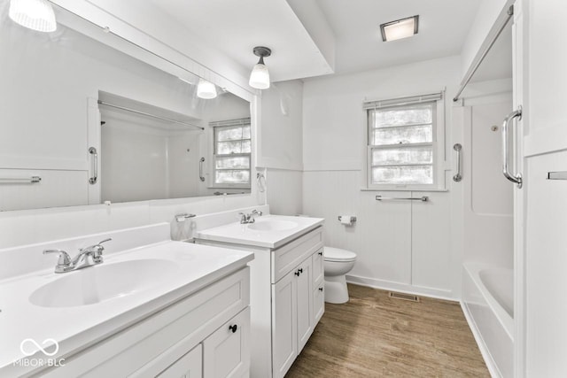 3200 Raible Ave, Anderson, IN 46011 - full bathroom with toilet, wood finished floors, a sink, two vanities, and wainscoting