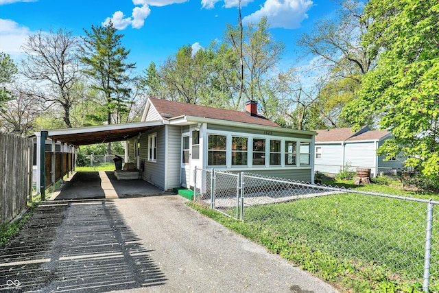 exterior space with an attached carport, fence, a chimney, and aphalt driveway