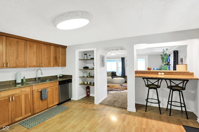 kitchen featuring a sink, brown cabinetry, light wood finished floors, and dishwasher
