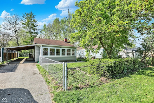 view of front of home featuring fence, a carport, a chimney, and driveway