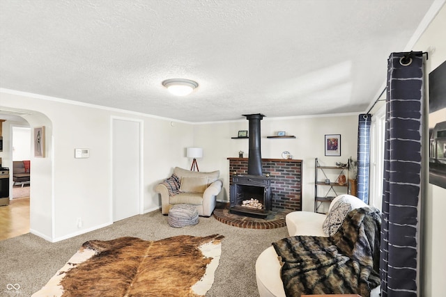 living room featuring crown molding, arched walkways, a wood stove, baseboards, and carpet flooring