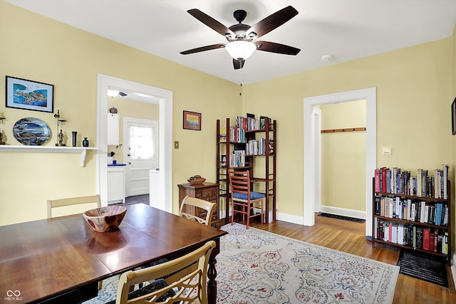 dining area with wood finished floors, a ceiling fan, and baseboards