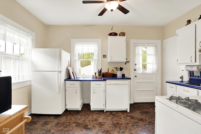 kitchen featuring white appliances, healthy amount of natural light, a ceiling fan, and dark countertops