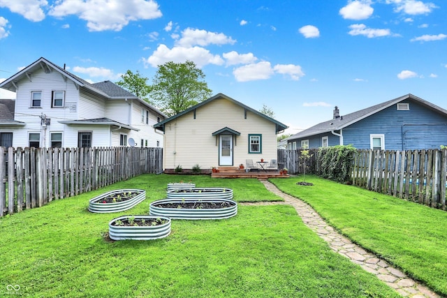 rear view of property with a vegetable garden and a wooden deck