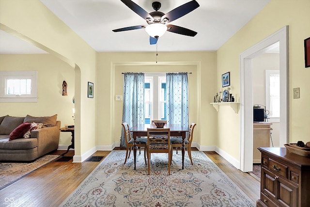 dining room with a ceiling fan, arched walkways, and wood finished floors