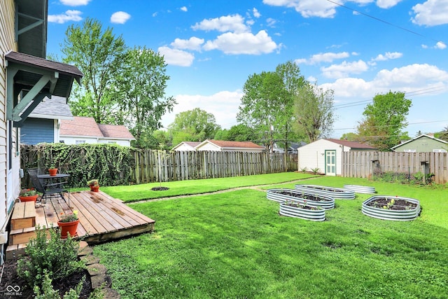 view of yard with a wooden deck, a vegetable garden, a storage shed, and an outdoor structure