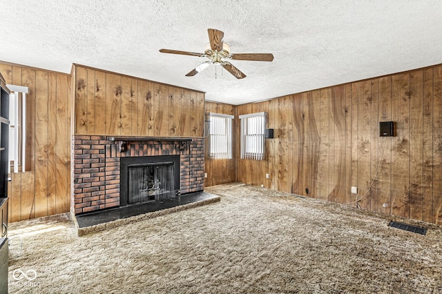 315 W High St, Pendleton, IN 46064 - unfurnished living room with wood walls, ceiling fan, a fireplace, a textured ceiling, and carpet floors