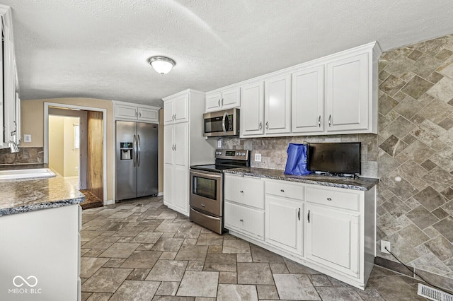 315 W High St, Pendleton, IN 46064 - kitchen with stainless steel appliances, white cabinetry, a sink, light stone finish flooring, and a textured ceiling