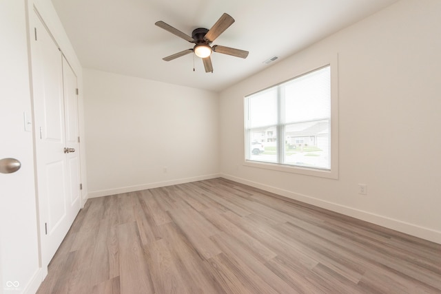 unfurnished bedroom featuring light wood finished floors, visible vents, baseboards, and a ceiling fan