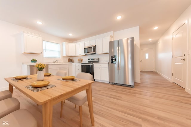 kitchen with light countertops, stainless steel appliances, white cabinets, and light wood finished floors