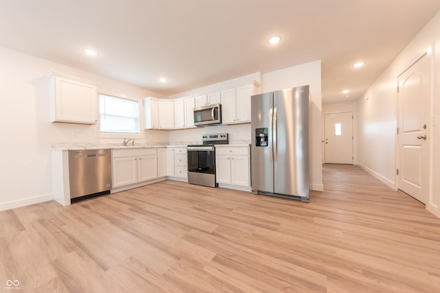 kitchen with light wood-type flooring, white cabinets, and appliances with stainless steel finishes