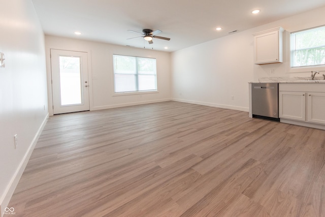 unfurnished living room featuring light wood-style floors, baseboards, ceiling fan, and a healthy amount of sunlight
